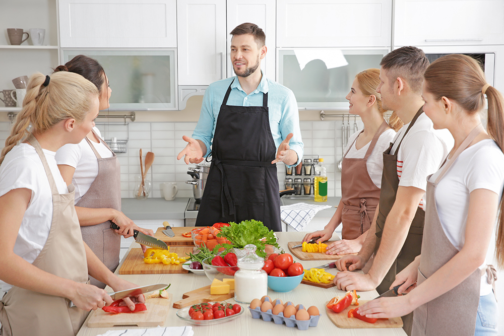 Male chef and group of people at group nutrition cooking classes