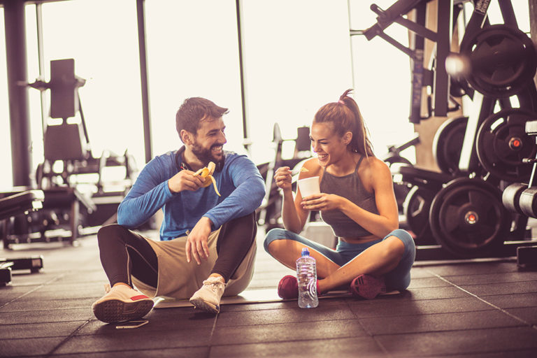 Sports Nutrition. Young couple at gym eating healthy food after exercise.