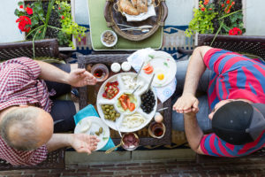 Two men pray before eating Greek food