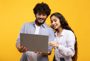 a man and a woman are looking at a laptop together