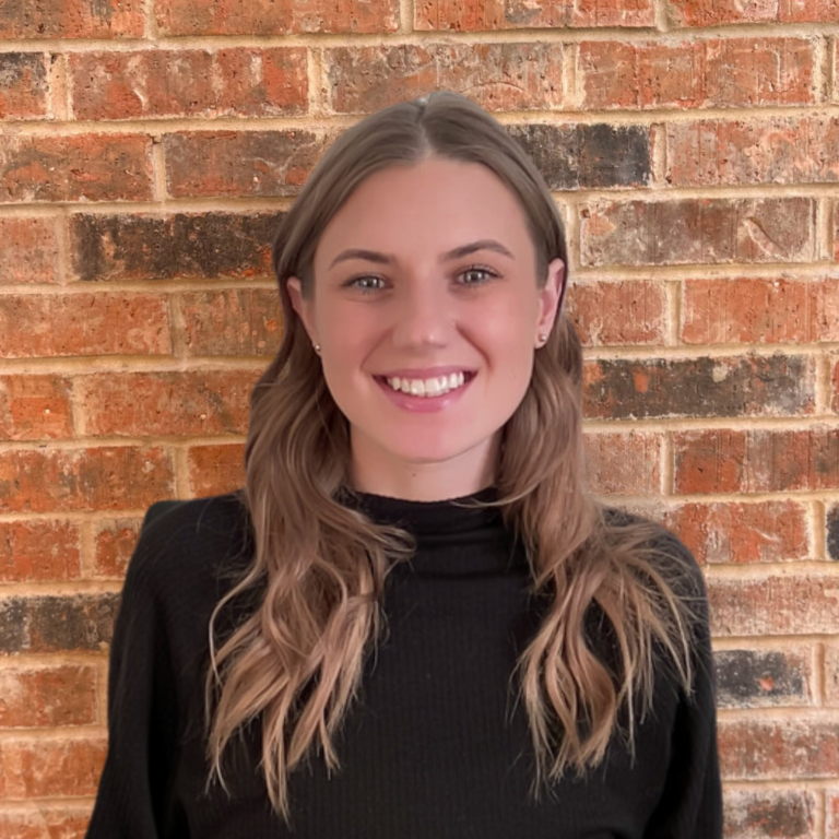 Anne-Marie smiling in front of a brick wall