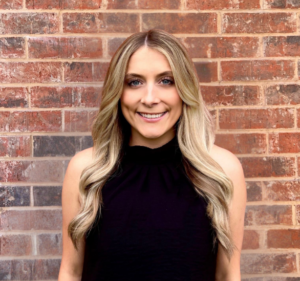 Natalie Larsen smiling in front of a brick wall