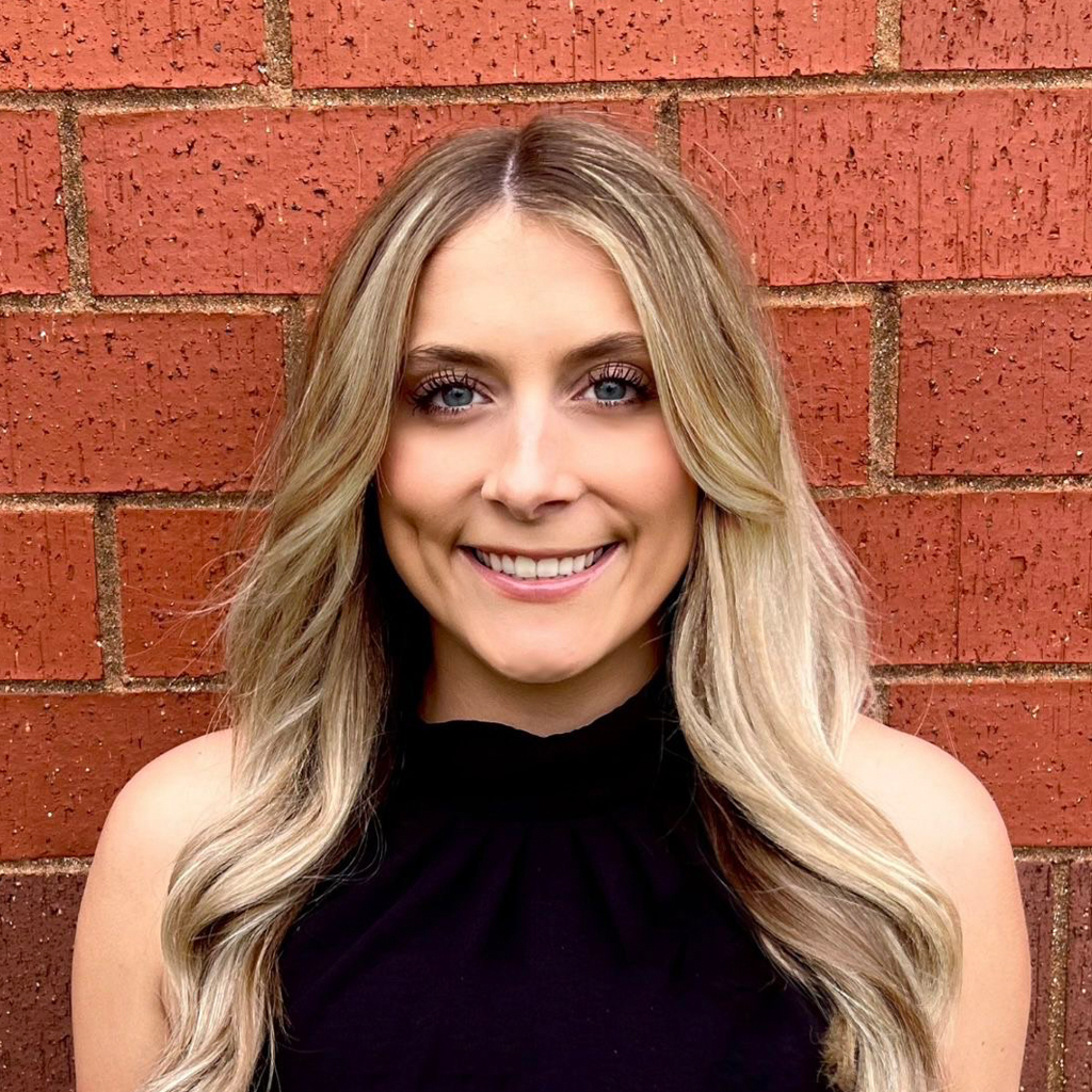 Natalie Larsen smiling in front of a brick wall