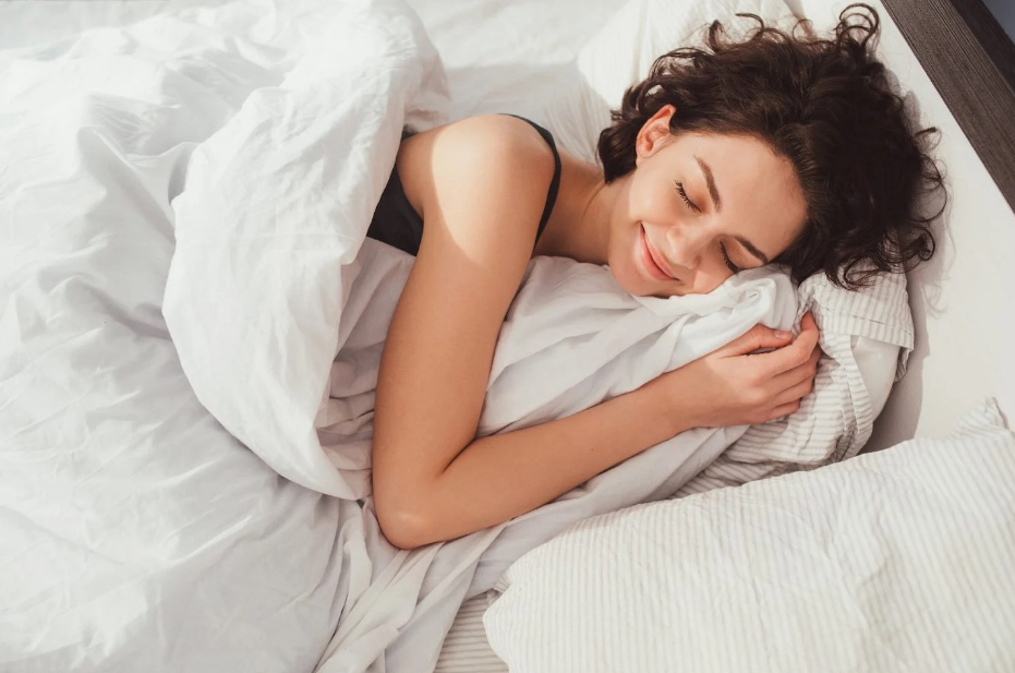 a woman smiling while sleeping in her bed