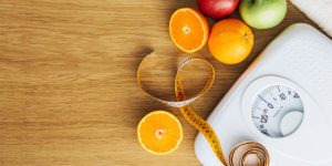 a measuring tape is laying on a scale next to oranges and apples