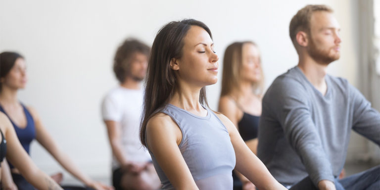 group of people doing yoga sitting with their eyes closed